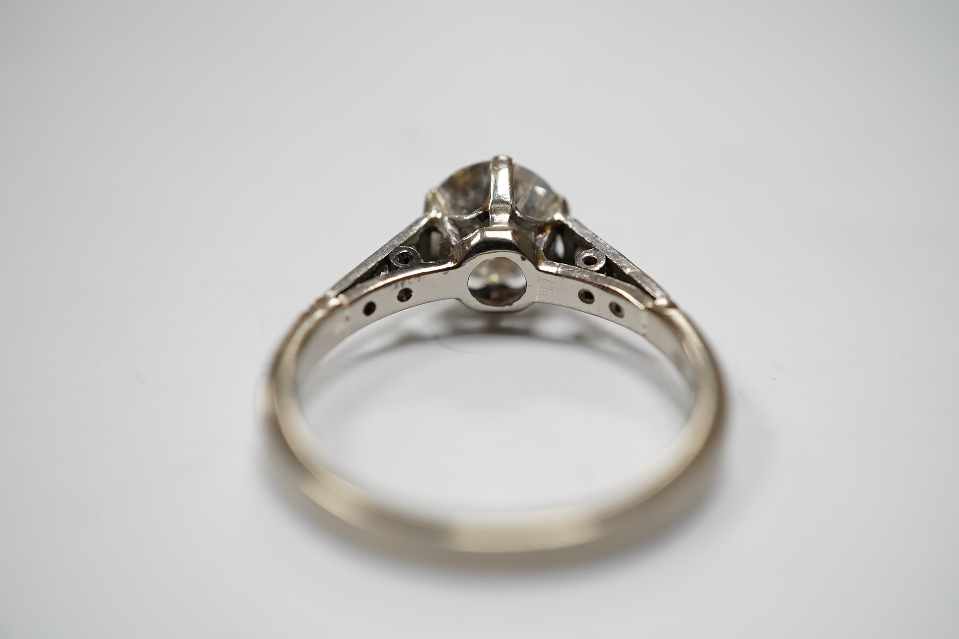 A white metal (stamped 18ct) and single stone diamond set ring, with six stone diamond set shoulders, the central stone weighing approximately 1.10ct, size M, gross weight 3.7 grams. Condition - poor to fair.